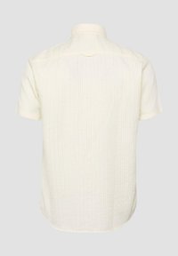 Chemise texturée écru à manches courtes avec de fines rayures verticales, vue de dos sur un fond uni gris clair.
