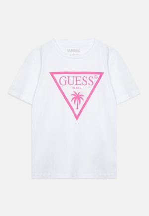Valge puuvillane t-särk, millel on suur roosa kolmnurkne logo koos tekstiga "GUESS BEACH" ning palmipuudega disain. Lühikesed varrukad ja ümmargune kaelus.