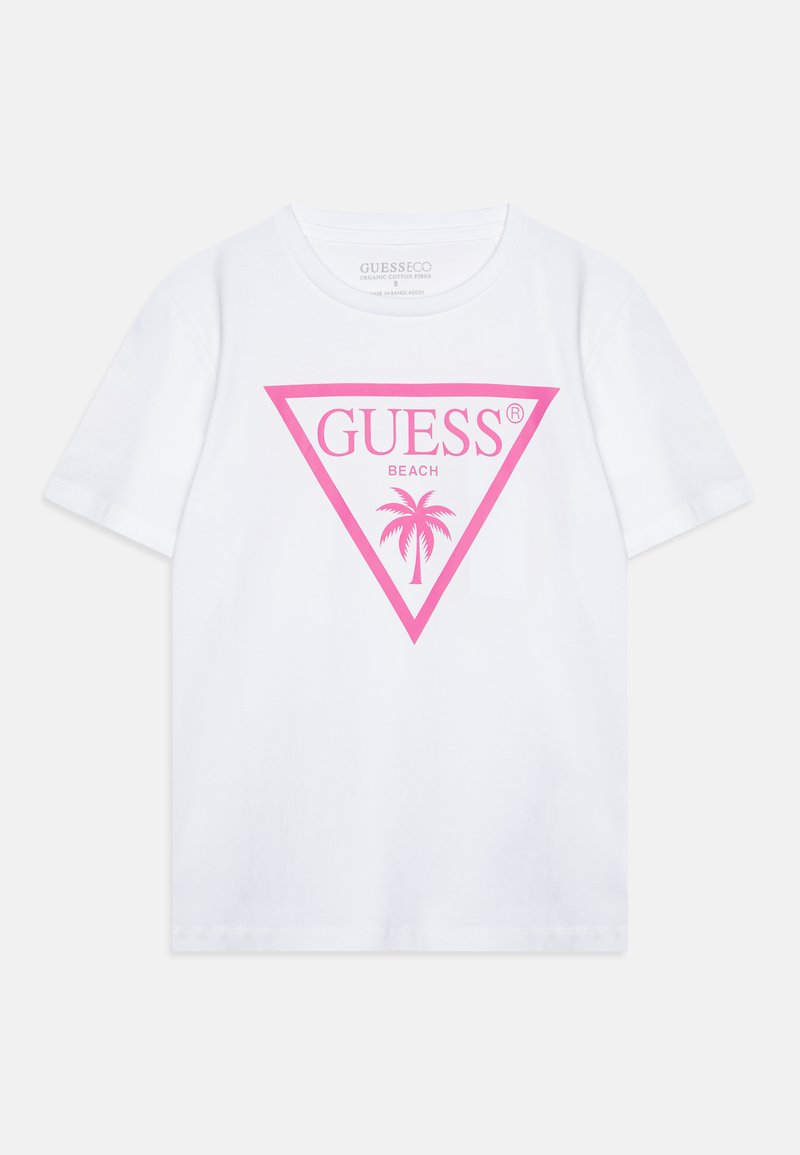 Bílé bavlněné tričko s velkým růžovým trojúhelníkovým logem, na kterém je nápis "GUESS BEACH" a design palmy. Krátké rukávy a kulatý výstřih.