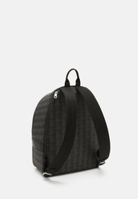 Rucsac negru cu un model geometric, având bretele ajustabile și un mâner de sus, fabricat din material durabil cu o textură netedă.