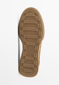 Suola di scarpa in gomma marrone con superficie testurizzata, caratterizzata da scanalature orizzontali e un'etichetta con marchio. Taglia 42 indicata.