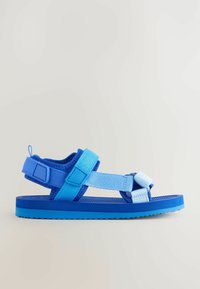 Blå sandal med justerbara remmar i två nyanser av blått, texturerad fotsula och en lätt sula med ett greppmönster.