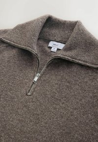 Pruun lukuga kaelusega kampsun, mis on valmistatud tekstuurse kootud kangaga. Omaduseks on kõrge krae, hõbedane lukk ja silt, mis näitab „NEXT RELAXED FIT“ suurust M.