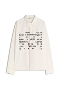 Camicia bianca a maniche lunghe con colletto abbottonato, caratterizzata da testo nero stampato sul davanti. Il testo include frasi riguardanti piani e crescita.
