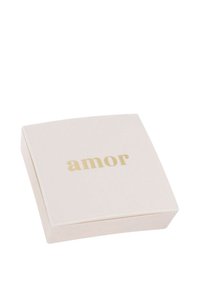 Kvadratisk, mjuk rosa låda med rundade hörn, som har ordet "amor" i guldtypografi på locket. Slät matt yta, inga synliga mönster.