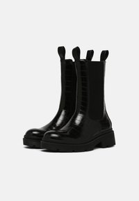Black ankle boots with a glossy crocodile pattern, elastic side panels, and pull tabs. Thick rubber soles provide added height and grip.