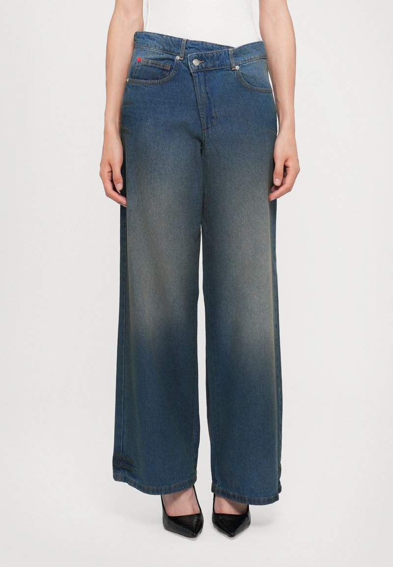 Široke jeans hlače iz temno modrega jeansa, z medenim pasom, dvema sprednjima žepoma in subtilnim zbledelim efektom.