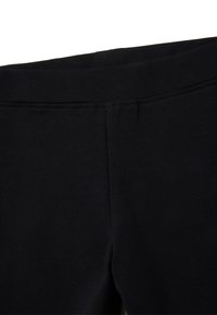 Leggings noirs fabriqués en tissu doux et extensible. Ils présentent une taille lisse et un design sans couture sans détails de couture visibles.
