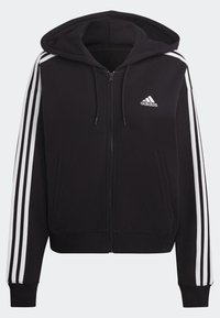 Svart Adidas zip-up hoodie med vita tre-stripe accenter på ärmarna, framfickor, dragsko på huvan och Adidas-logotyp på bröstet.