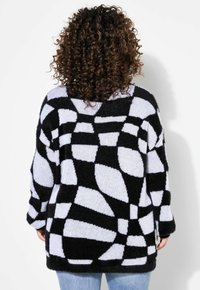 Maglione lavorato a maglia nero e azzurro chiaro oversize con un motivo geometrico, dotato di maniche lunghe e orlo posteriore scollato. Tessuto morbido e texture.