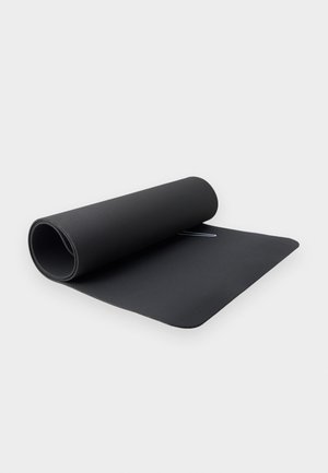 Μερικώς διπλωτό μαύρο στρώμα γυμναστικής πάνω σε λευκή επιφάνεια με ένα διακριτικό λευκό λογότυπο κοντά στο κέντρο.