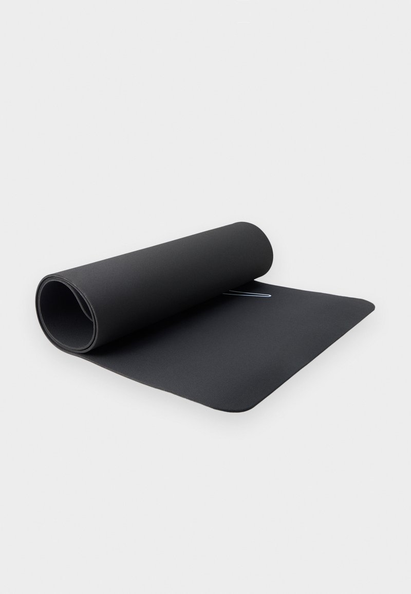 Μερικώς διπλωτό μαύρο στρώμα γυμναστικής πάνω σε λευκή επιφάνεια με ένα διακριτικό λευκό λογότυπο κοντά στο κέντρο.