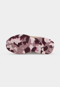 Semelle de chaussure avec motif de bande de roulement rugueux et texturé en beige, marron foncé et camouflage rose sur fond blanc.