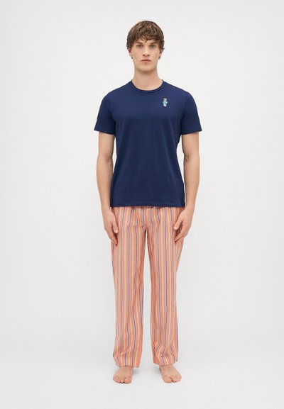T-shirt à manches courtes bleu marine avec un petit graphic sur la poitrine, associé à un pantalon de pyjama long rayé en orange, bleu et blanc.