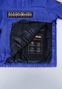 Modrá bunda se zipem vpředu, prošívanou černou podšívkou a značkovou etiketou. Obsahuje ikony pro voděodolnost, větruodolnost a prodyšnou tkaninu.
