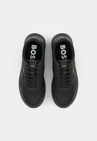 Sneaker nere con una toma superiore in sintetico liscio, punta rotonda, design con lacci, dettagli testurizzati e marchio "BOSS" sulle sole interne.