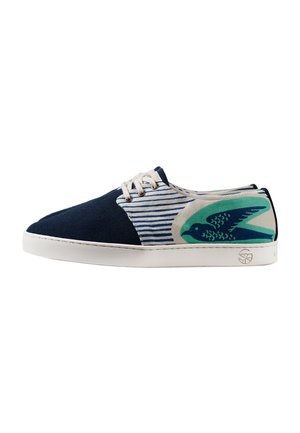 Baskets bleu marine et blanches avec lacets blancs, motif rayé et graphique d’oiseau bleu sarcelle sur le talon, semelle en caoutchouc blanche, vue de côté.