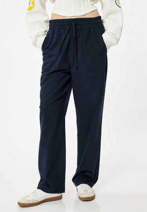 Marineblauwe ontspannen pasvorm sweatpants met een elastische tailleband en trekkoord, voorzien van zijzakken en een gladde textuur.