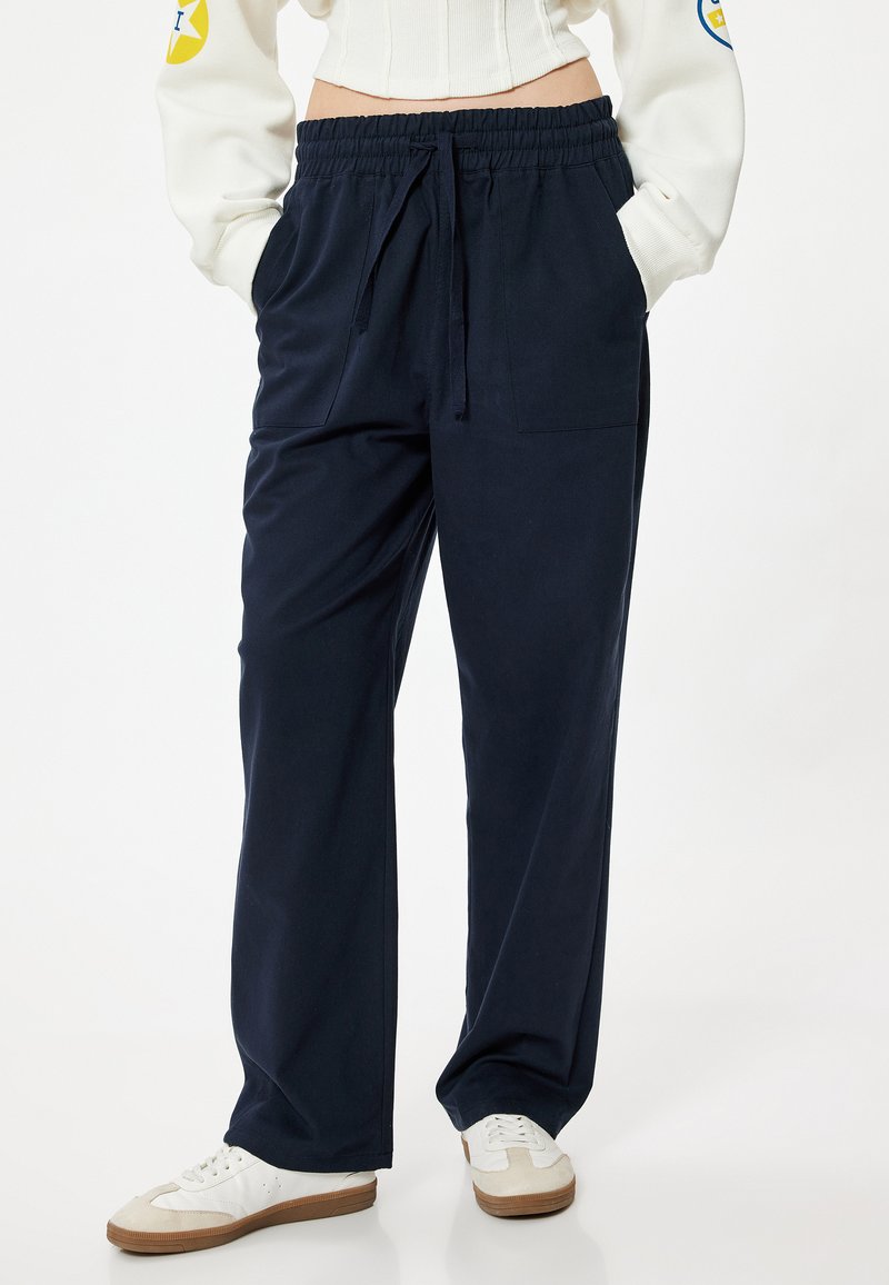 Pantalones de chándal en azul marino de corte relajado con cintura elástica y cordón, que cuentan con bolsillos laterales y una textura suave.