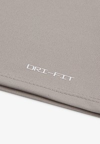 Grey DRI-FIT fabric with a ribbed texture, featuring white branding stitching at the edge, highlighting a smooth finish.
