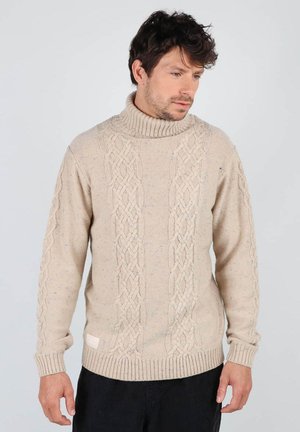 Pull en maille beige avec col roulé, design en torsades, poignets et ourlet côtelés, et détails en texture mouchetée. Présente une petite étiquette de marque.