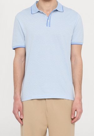 Polo bleu clair avec un motif en losanges texturé, col et poignets de manches bleus contrastants, doté d'une patte de boutonnage à deux boutons.