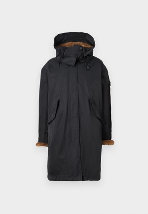 Dlhý čierny parkas s kapucňou podšitou kožušinou, bočnými vreckami a hnedými kožušinovými akcentmi na manžetách. Vyrobený z vodoodolného materiálu.