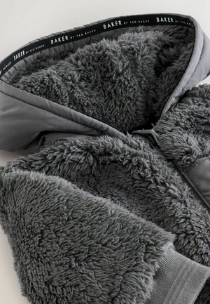 Gray hooded jacket featuring soft, fuzzy textured fabric with a smooth outer layer. Branding displayed on the inner lining.