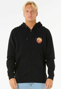 Sort zip-up hoodie lavet af blødt stof, med en frontlomme og en dekorativ rund lap med farverigt design.