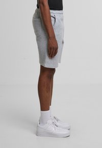 Grå bomuldsshorts med elastisk talje, sidelommer og en afslappet pasform, bæres med hvide sneakers og sokker. Sidevinkel.