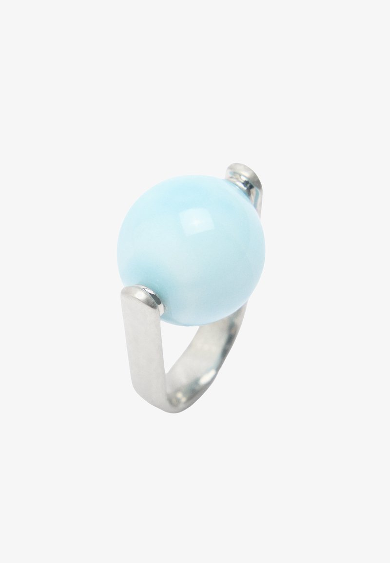 Srebrny pierścionek o otwartym designie z dużym, gładkim, okrągłym, jasnoniebieskim kamieniem osadzonym w centrum.