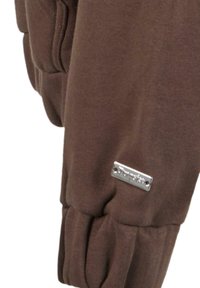 Hnedá mikina so mäkkou textúrou, s striebornou logom na rukáve a elastickými manžetami pre tesné priliehanie.