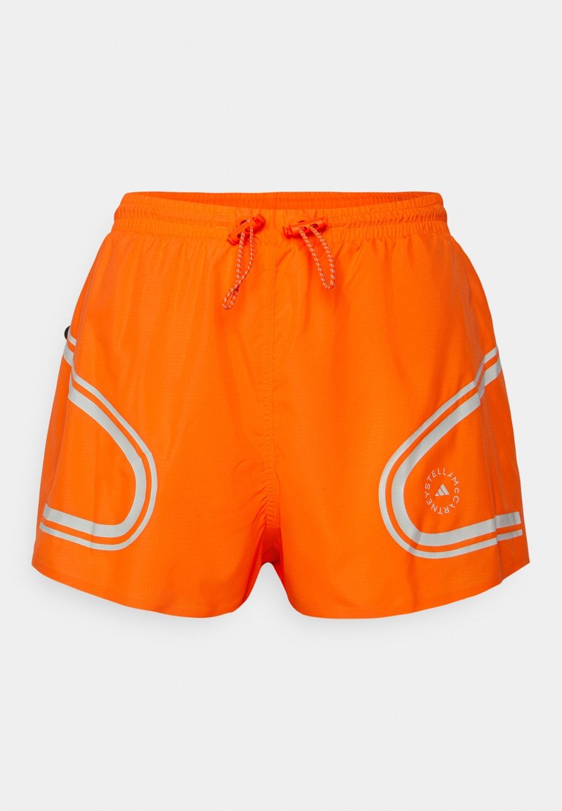Pantaloni sportivi arancioni brillanti con bordature argento riflettente, vita elastica e lacci, con un logo circolare sulla gamba destra.