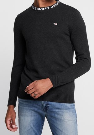 Maglione nero a maglia con colletto rotondo e scritta "TOMMY JEANS", polsini e orlo a costine, e un piccolo logo sul petto.