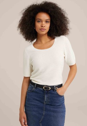 Suéter blanco texturizado de manga corta y cuello redondo, combinado con una falda de mezclilla azul y un cinturón negro con hebilla dorada.