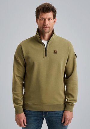 Sweat-shirt vert olive avec un col zippé, fabriqué à partir d'un matériau doux. Présente un petit logo brodé sur la poitrine et des poignets côtelés.