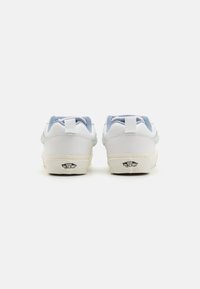 White sneakers with light blue accents, a smooth leather finish, padded collar, and classic rubber outsole featuring logo details.