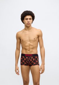 Boxeri negri cu model floral în roșu și portocaliu, cu o talie contrastantă roșie inscripționată cu logo-ul „DIESEL”.