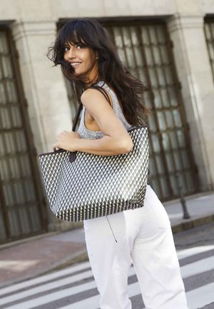 Woven tote bag featuring a geometric black and white pattern, sturdy handles, spacious design, and a textured finish.
