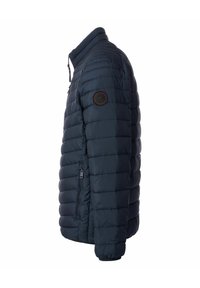Marineblauer Steppjacke mit hohem Kragen, gestepptem Design, seitlicher Reißverschlusstasche und einem runden Logo-Patch auf dem linken Ärmel.