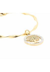 Bracciale in oro con torsione, dotato di un ciondolo circolare con un design ad albero, circondato da pietre trasparenti che aggiungono contrasto visivo e texture.