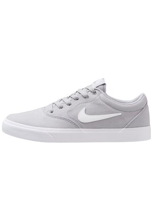 Basket basse grise Nike avec le swoosh blanc, fermeture à lacets et semelle en caoutchouc blanche, vue de côté sur fond blanc.