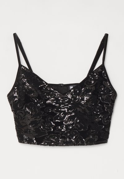 Crop top en sequins noirs avec un motif texturé, décolleté en V, fines bretelles ajustables et fermeture éclair au dos. Surface brillante qui reflète la lumière.