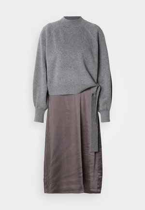 Pulôver cinza tricotado com decote curvado e mangas longas, combinado com uma saia fluida em tom mauve com detalhe de laço lateral. Texturas suaves e design elegante.