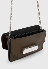 Brun læder skuldertaske med en sølvfarvet kædestrop, der har et elegant design, en metal-lukning og en kontrasterende sort indvendig.