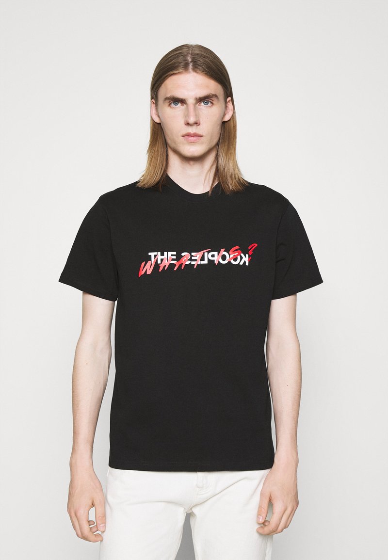 Schwarzes Baumwoll-T-Shirt mit kurzen Ärmeln, das grafischen Text mit "THE" und "WHAT?" in kontrastierenden weißen und roten Farben zeigt.