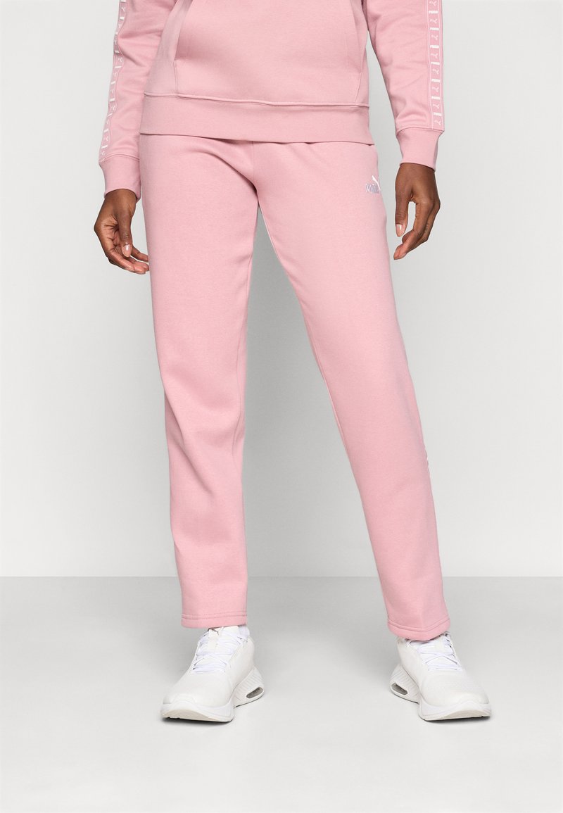 Roze katoenen joggers met een slim fit, voorzien van een wit logo op de linkerdij en ribgebreide boorden bij de enkels. Gecombineerd met witte sportschoenen.