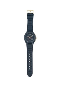 Orologio in gomma nera con quadrante rotondo, accenti dorati e rossi, e cinturino testurizzato con fori a taglio per una vestibilità regolabile.