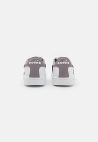 Sneaker grigi e bianchi con una texture liscia, forma arrotondata, design minimalista e il logo "diadora" sul tallone.