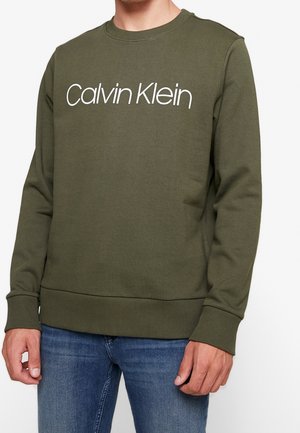 Sudadera verde oliva con cuello redondo, puños y dobladillo acanalados. Presenta el logo blanco de "Calvin Klein" en una fuente moderna en la parte frontal.
